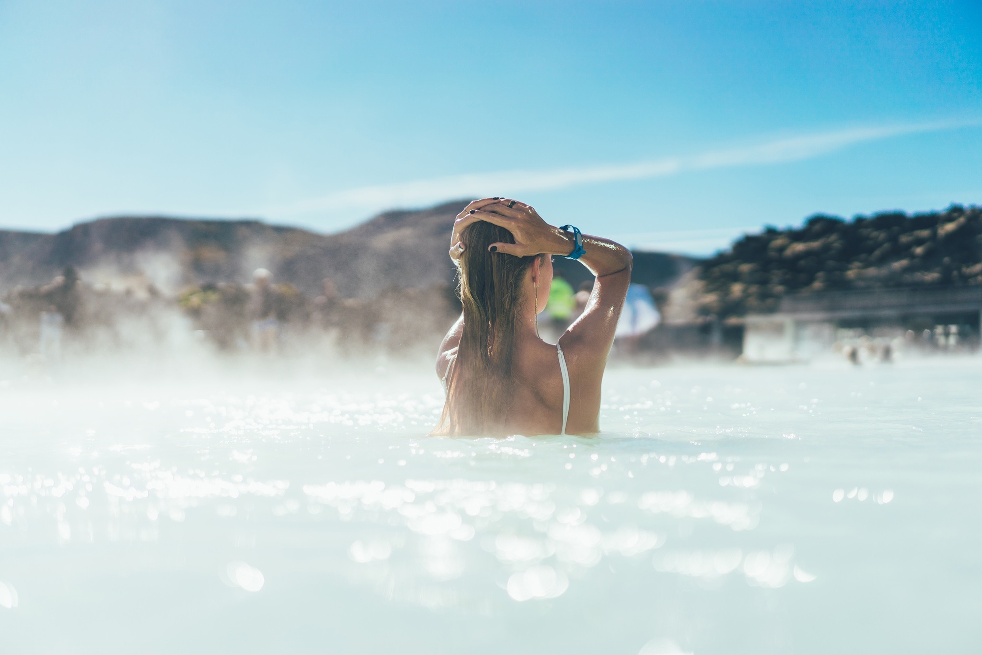 back view of young woman relaxing in hot pool in Iceland