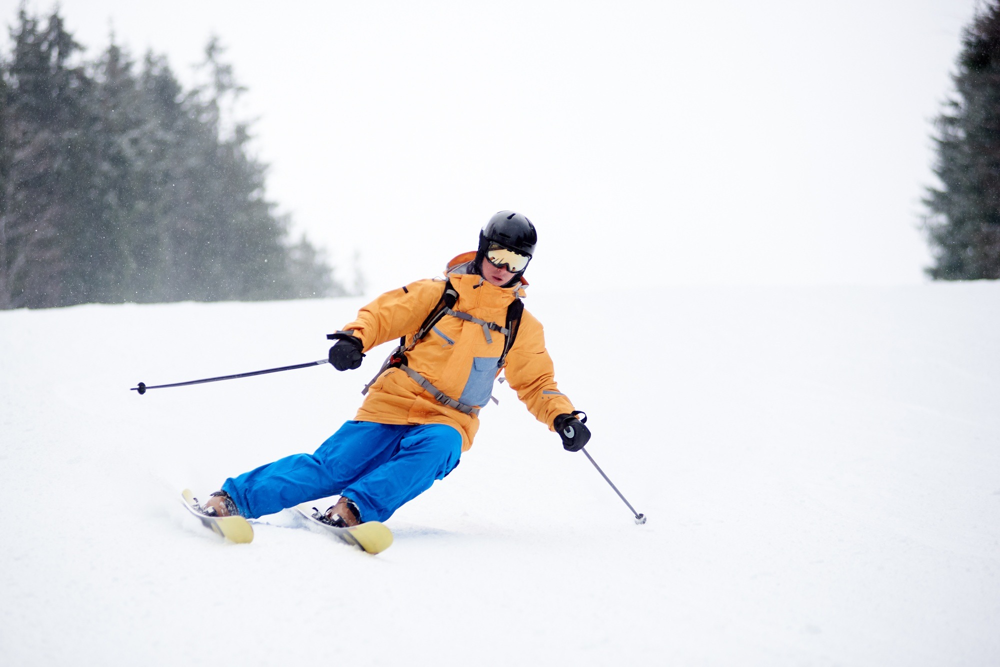 Young man skier in ski sportswear doing skillful maneuvers on skis.